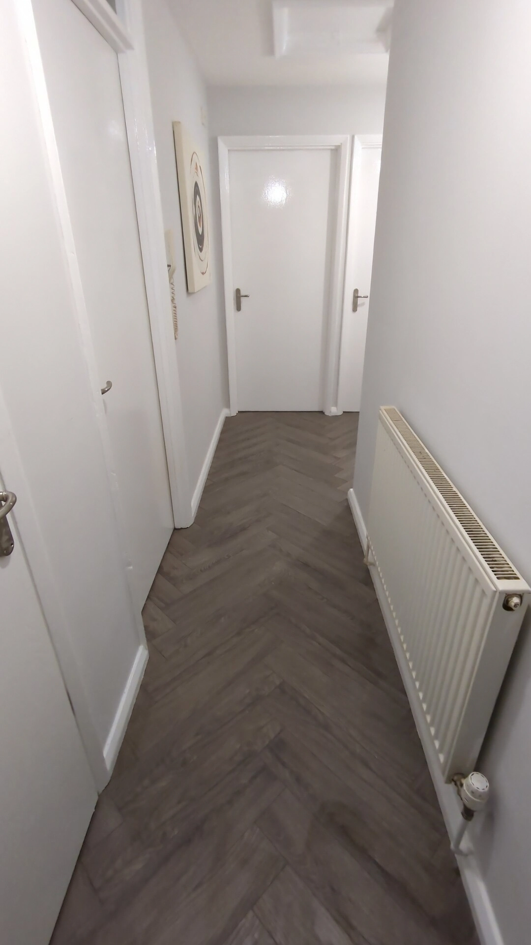 Finished grey oak herringbone laminate floor in a Pontefract hallway with white skirtings refitted