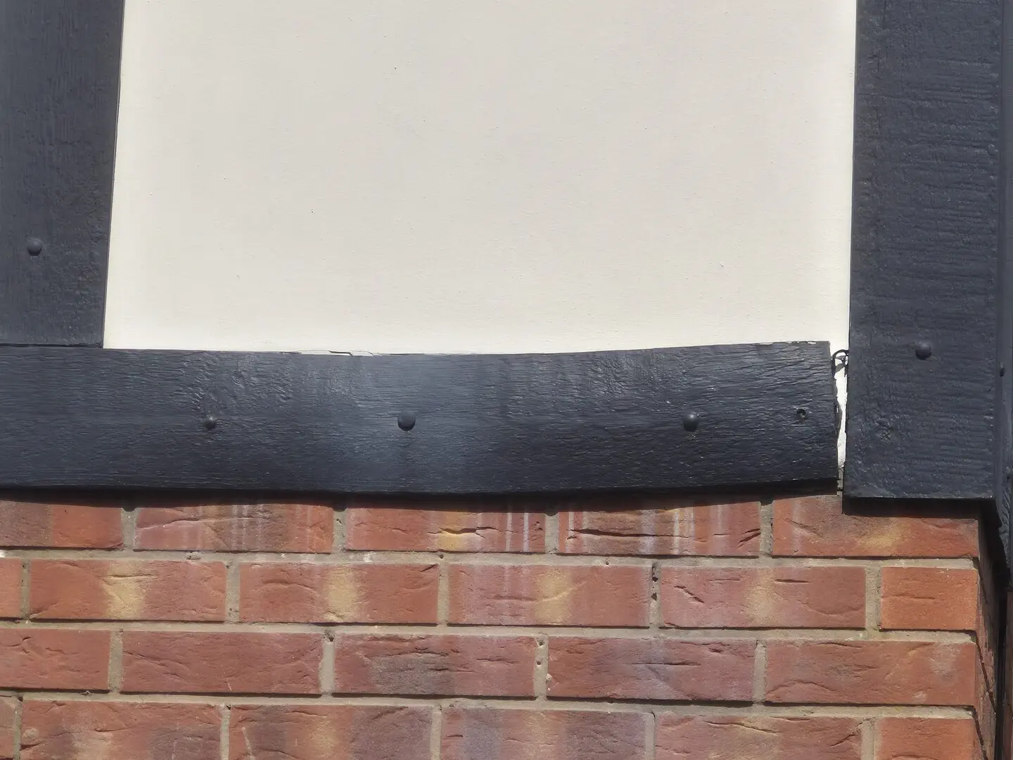 Close-up of a bowed mock-Tudor board pulled away from the vertical board leaving a visible gap