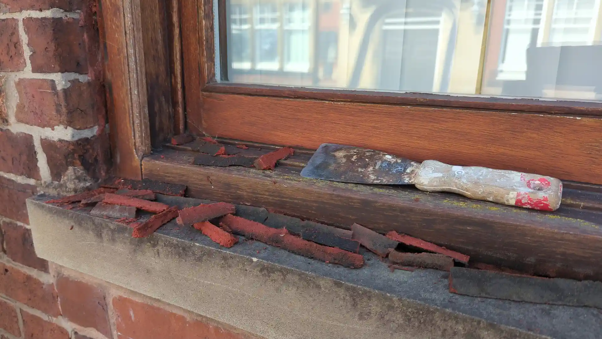 Old failed window frame sealant cut out and lying on the stone sill