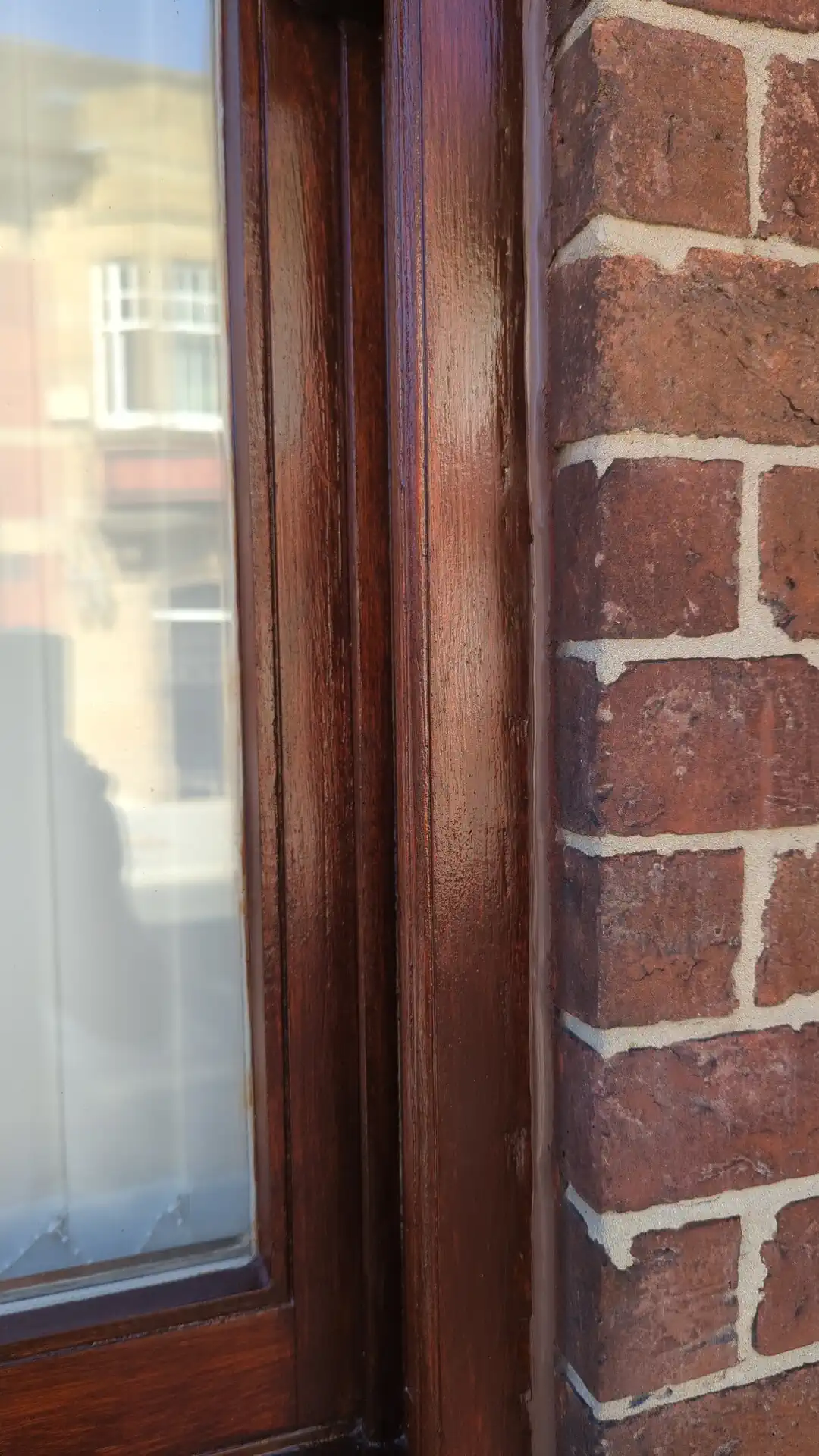 New sealant bead closing the joint between a repaired timber window frame and brickwork