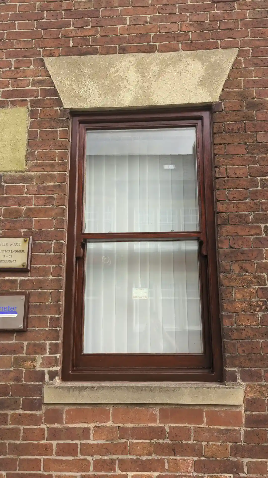 Timber sliding sash window finished in mahogany woodstain with clean profiles and renewed sealant
