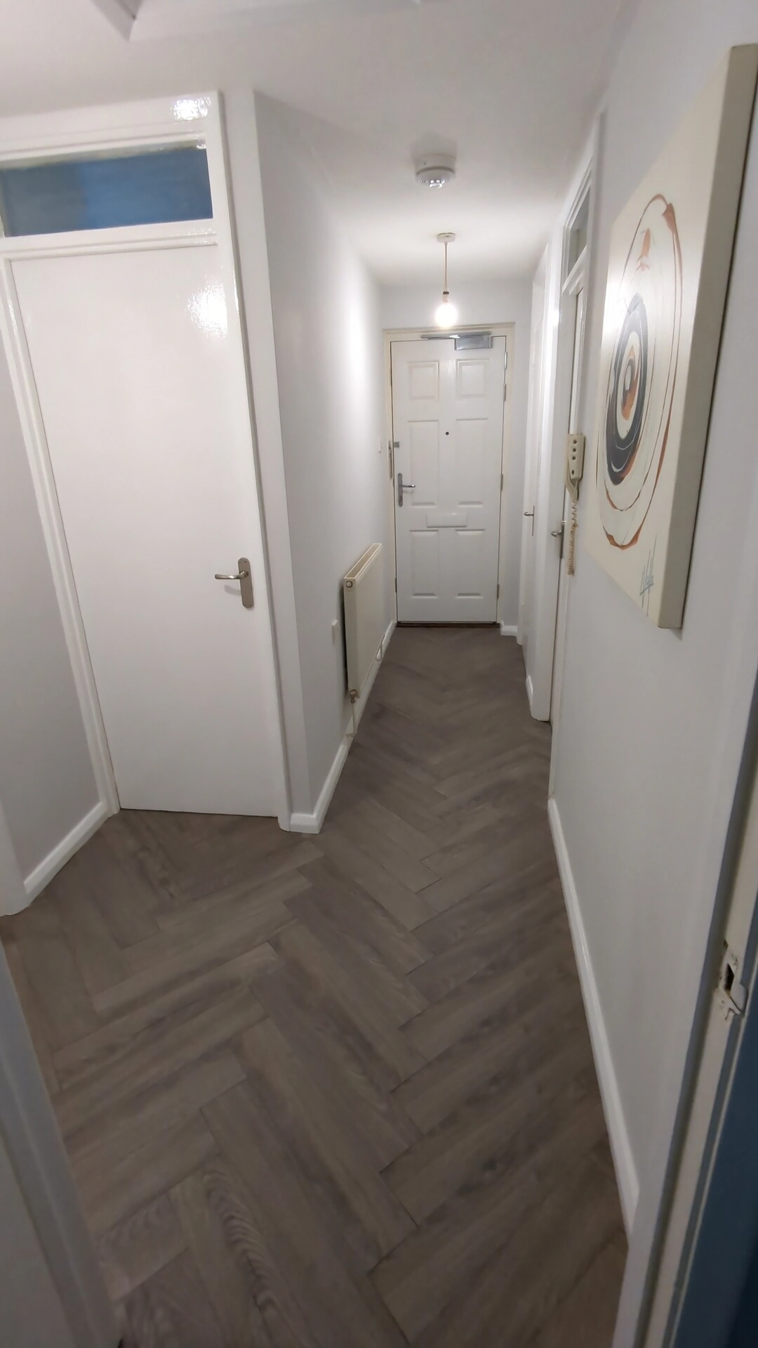 Grey oak herringbone laminate flooring running the length of a Pontefract hallway to the front door