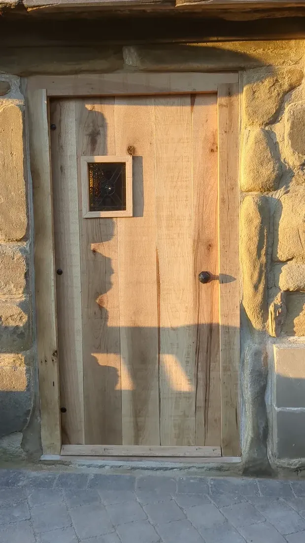 Solid oak boarded door with stained-glass detail in a stone surround