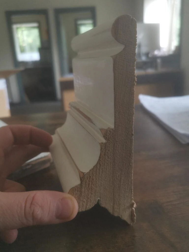 Hand holding the cut end of an unknown moulding, showing its profile