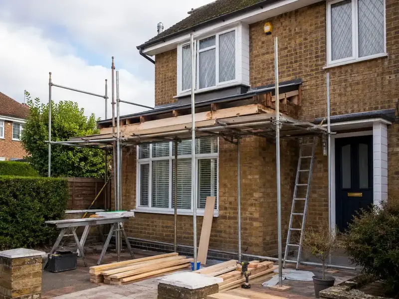 Timber roof frame under repair on a scaffolded house extension