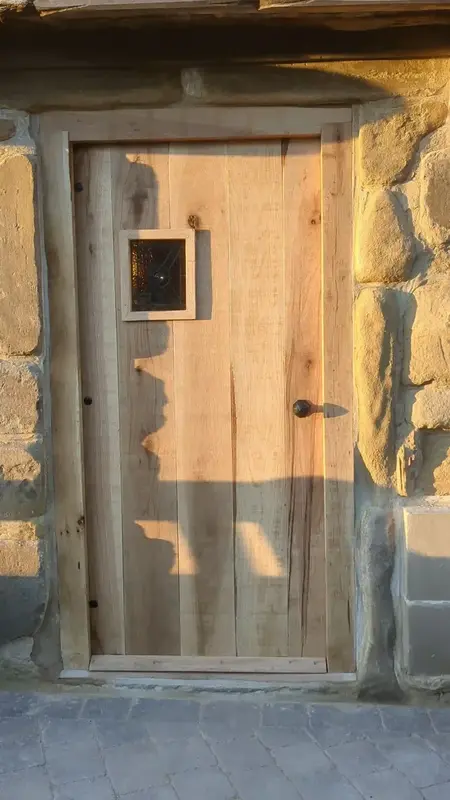 Oak front door with a small glazed panel in a stone opening