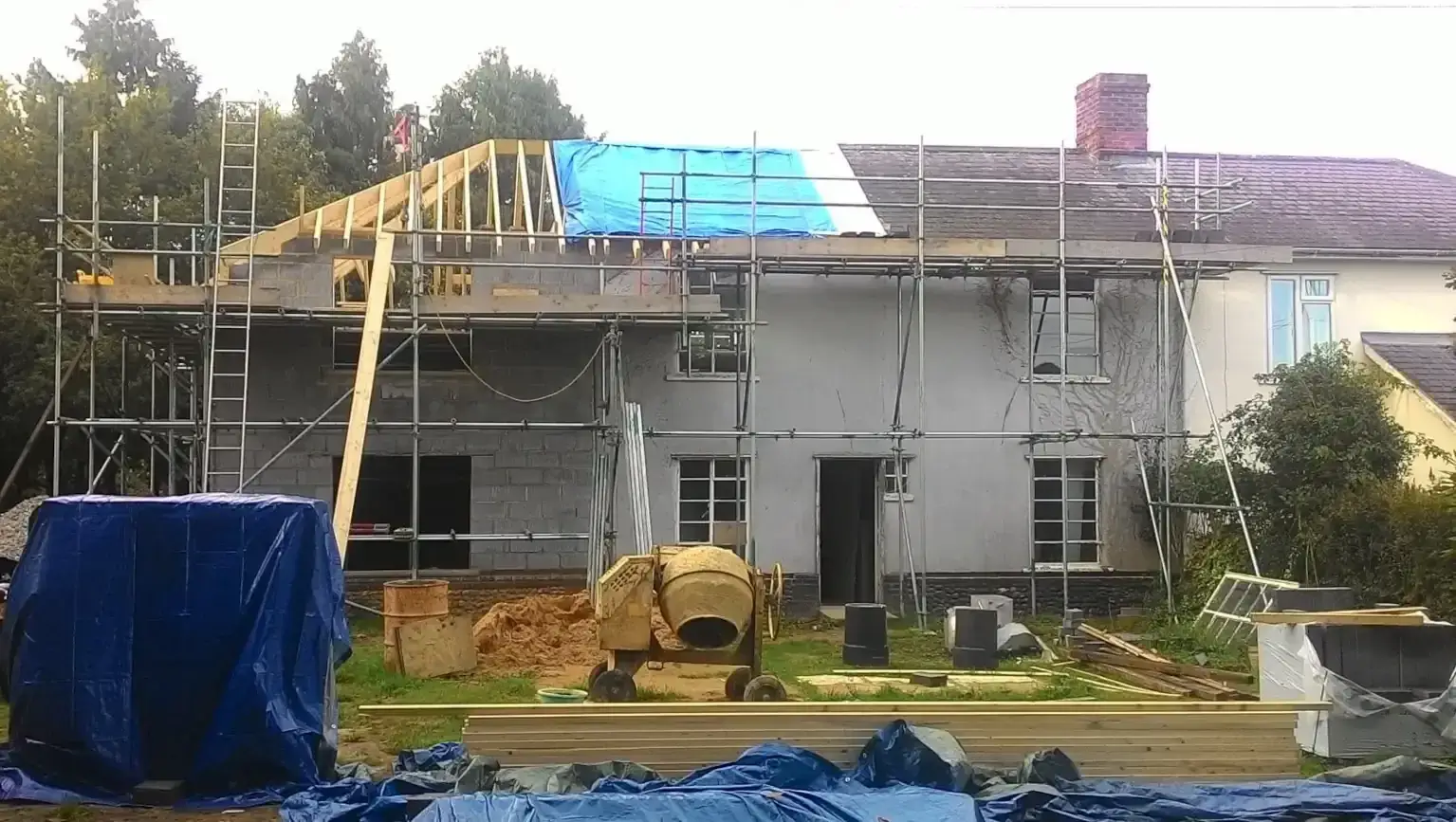 Hipped roof timbers going up on a scaffolded house extension