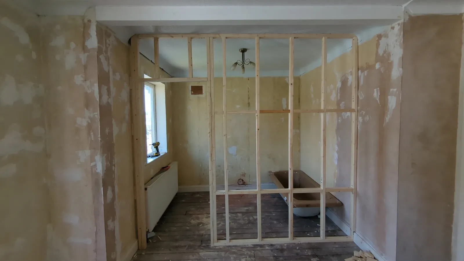 Timber stud partition frame with door studs and noggins set out in a stripped-back room