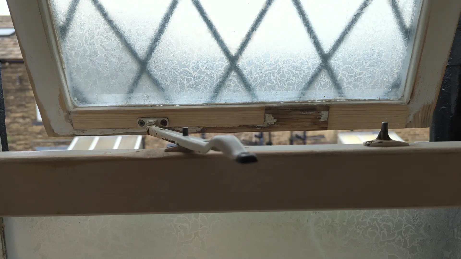 Repaired casement window refitted and opening on its stay, new timber visible before decoration